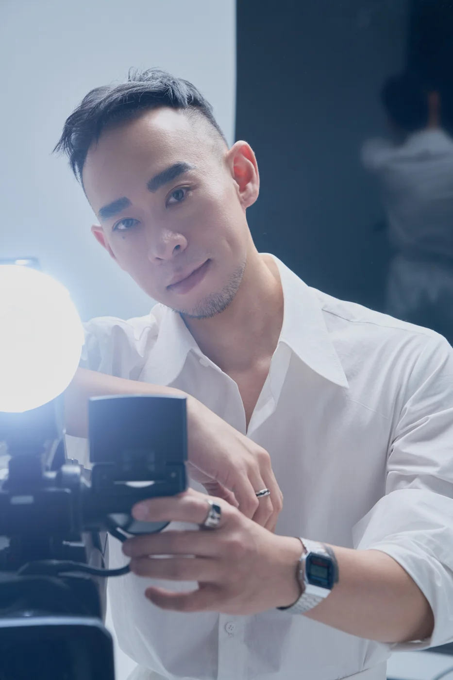 Kane Diep holding a camera in a white shirt